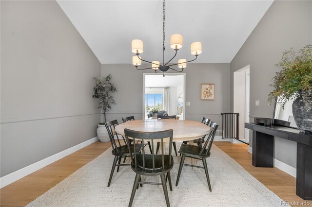 dining space with baseboards, an inviting chandelier, and light wood-style flooring