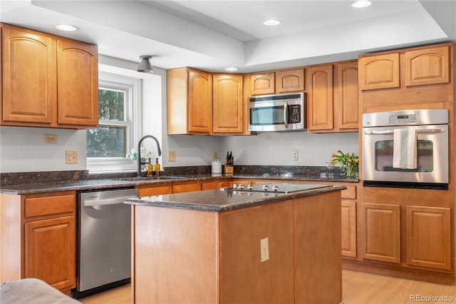 kitchen with a kitchen island, appliances with stainless steel finishes, a sink, dark stone countertops, and recessed lighting
