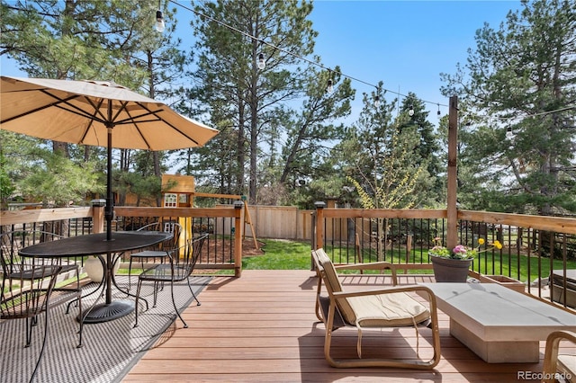 wooden terrace with a fenced backyard and a playground