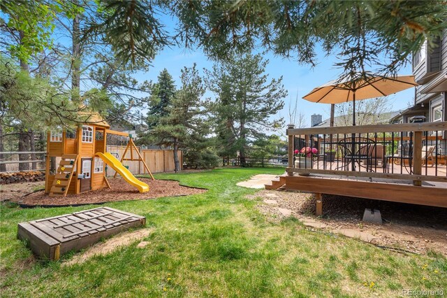 view of yard featuring fence, a playground, and a deck