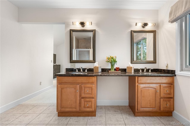 bathroom with double vanity, baseboards, a sink, and tile patterned floors