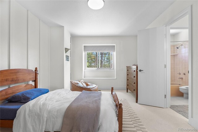 bedroom with ensuite bathroom and light carpet