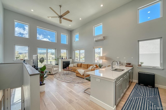 living area featuring baseboards, a glass covered fireplace, a wall unit AC, light wood-style flooring, and recessed lighting