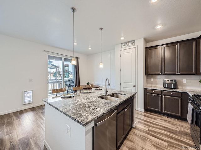 kitchen featuring sink, light stone counters, dishwasher, black range with gas stovetop, and pendant lighting