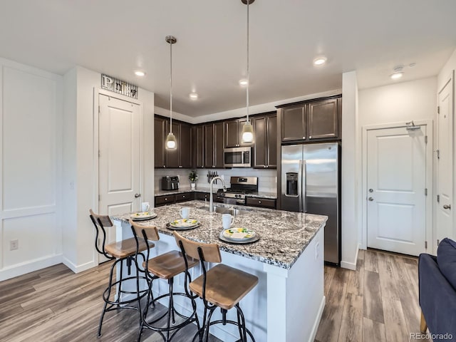 kitchen featuring pendant lighting, stainless steel appliances, dark brown cabinets, and hardwood / wood-style flooring