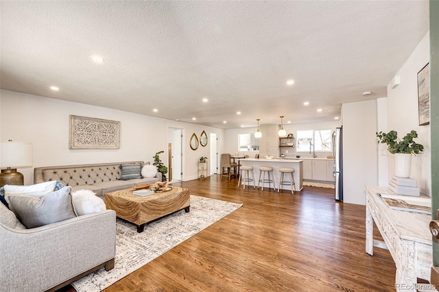 living area with a textured ceiling, dark wood-type flooring, and recessed lighting