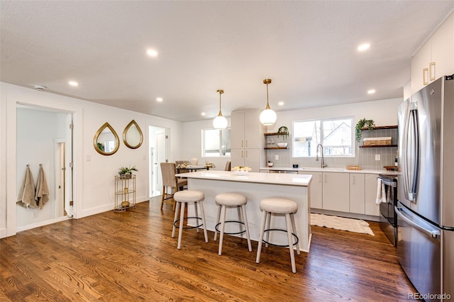 kitchen with a center island, range with electric stovetop, open shelves, freestanding refrigerator, and a kitchen bar