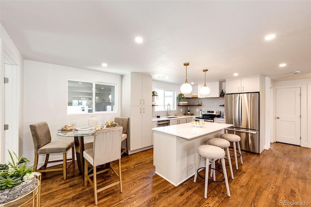 kitchen featuring appliances with stainless steel finishes, light countertops, dark wood-type flooring, and a center island