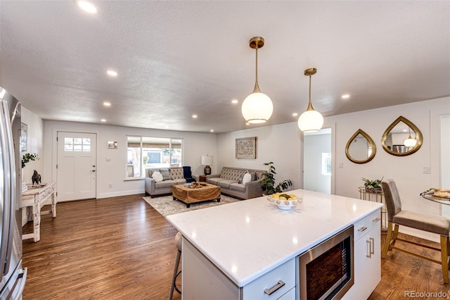 kitchen with dark wood-type flooring, built in microwave, a center island, and light countertops