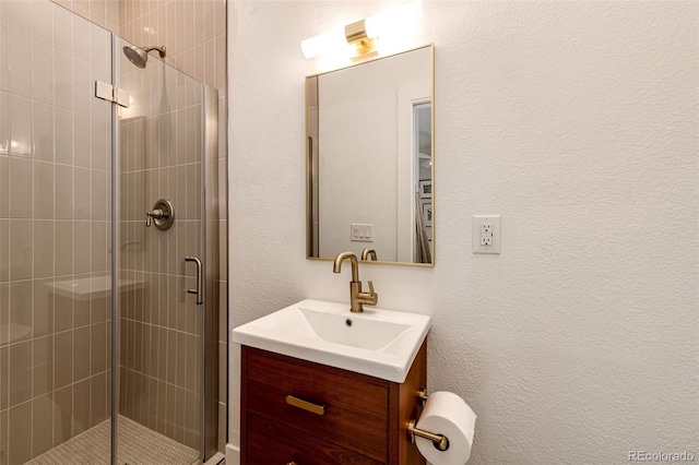 full bath with a stall shower, a textured wall, and vanity