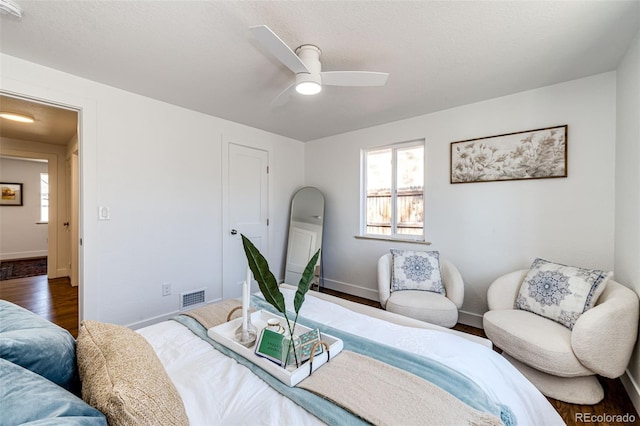 bedroom featuring a ceiling fan, wood finished floors, visible vents, and baseboards