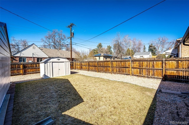 view of yard with a shed, a fenced backyard, and an outbuilding