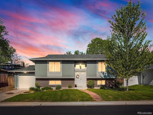 6869 Quay St, Arvada, CO 80003 - split foyer home with brick siding, concrete driveway, an attached garage, and a shingled roof