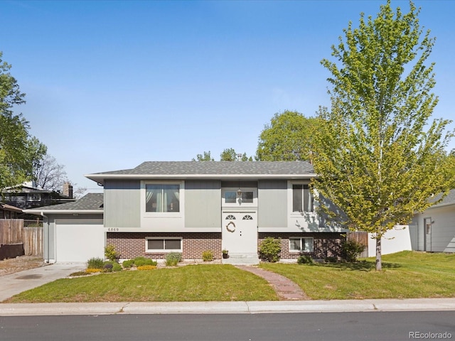 6869 Quay St, Arvada, CO 80003 - split foyer home with driveway, a garage, brick siding, and a shingled roof