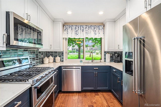 kitchen with blue cabinets, appliances with stainless steel finishes, sink, and white cabinets