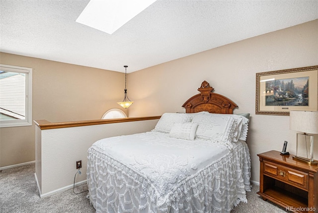 bedroom featuring a skylight, carpet, baseboards, and a textured ceiling