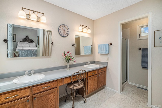 bathroom featuring double vanity, a shower stall, a textured ceiling, and a sink