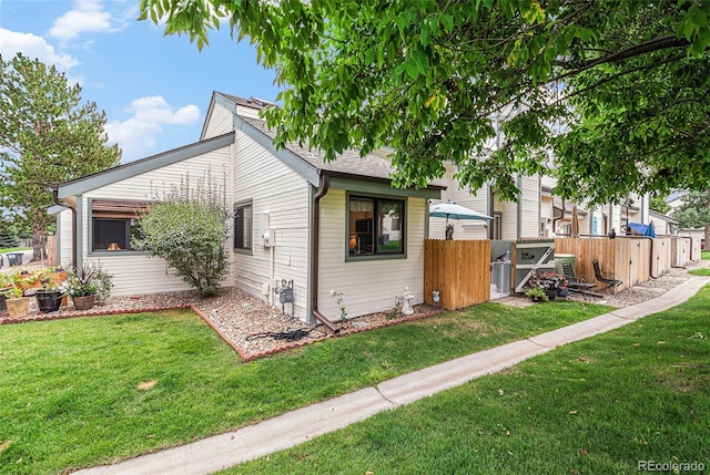 exterior space with a shingled roof, fence, and a front yard