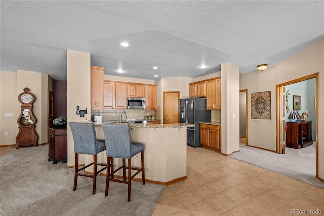 kitchen featuring light colored carpet, kitchen peninsula, black refrigerator with ice dispenser, decorative backsplash, and a breakfast bar area