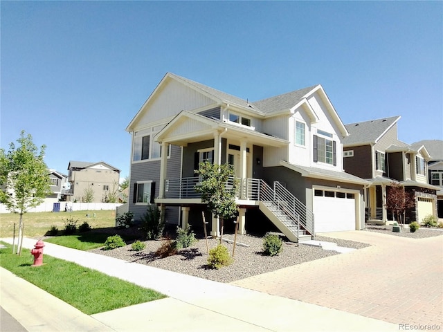 view of front of property with a garage, a residential view, decorative driveway, and stairway