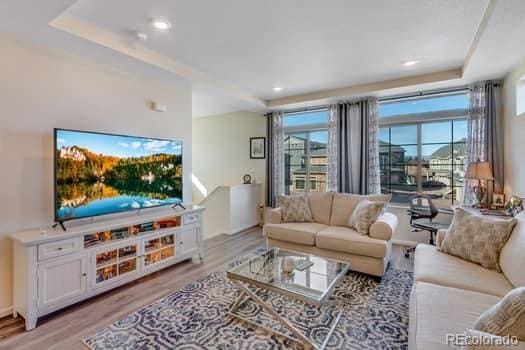 living area with a raised ceiling and light wood finished floors