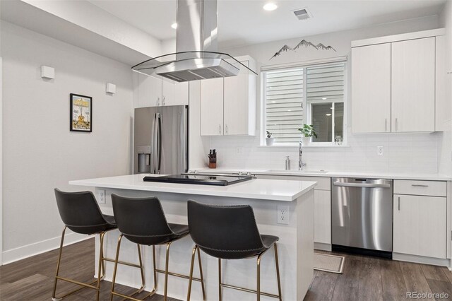1284 Quitman St, Denver, CO 80204 - kitchen with appliances with stainless steel finishes, island range hood, a kitchen island, a breakfast bar area, and decorative backsplash