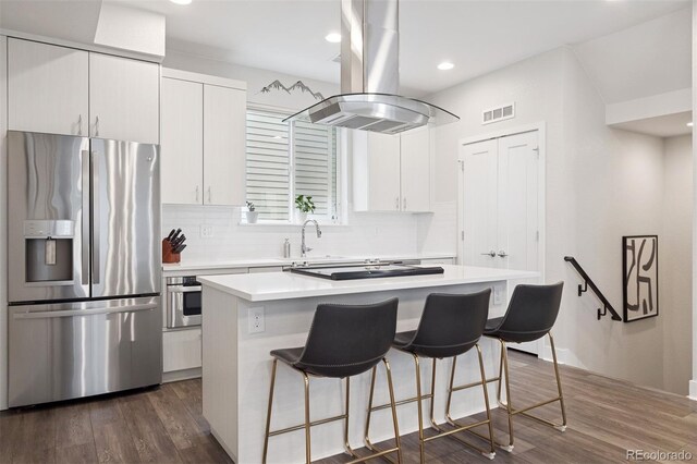1284 Quitman St, Denver, CO 80204 - kitchen featuring appliances with stainless steel finishes, island exhaust hood, a center island, a breakfast bar, and recessed lighting