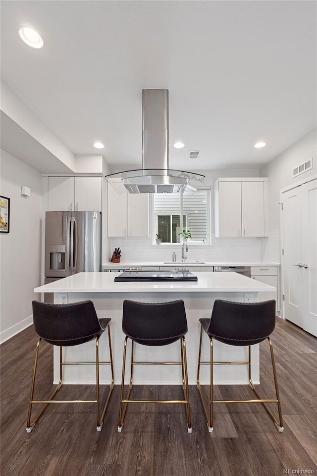 1284 Quitman St, Denver, CO 80204 - kitchen featuring stainless steel refrigerator with ice dispenser, island exhaust hood, dark wood-style floors, light countertops, and a kitchen island