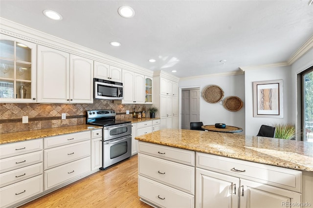 kitchen featuring stainless steel appliances, white cabinets, glass insert cabinets, and light stone countertops