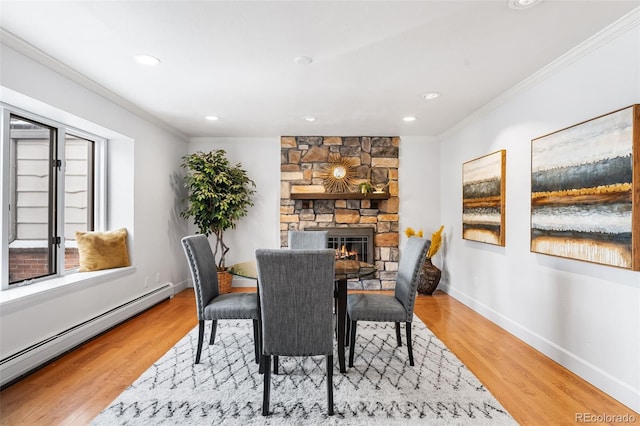 dining area featuring baseboards, baseboard heating, crown molding, and wood finished floors