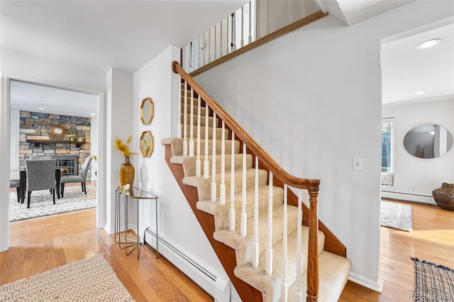 staircase featuring baseboard heating, recessed lighting, wood finished floors, and baseboards