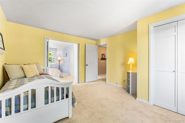 bedroom with baseboards, a closet, and light colored carpet