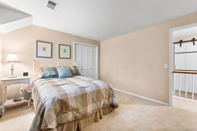 bedroom with light carpet, a barn door, visible vents, baseboards, and a closet