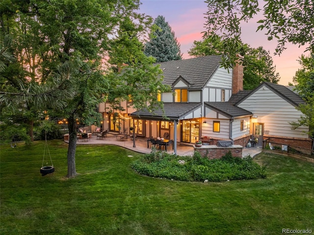 back of house featuring a yard, a chimney, outdoor lounge area, and a patio