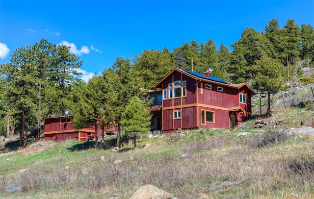 548 Coughlin Meadows Rd, Boulder, CO 80302 - back of house featuring a chimney, a view of trees, and a wooden deck