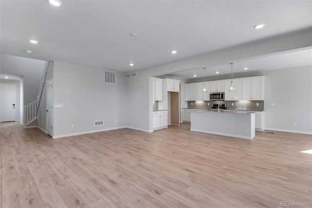 13502 E 100th Ave, Commerce City, CO 80022 - unfurnished living room featuring light wood-type flooring, recessed lighting, baseboards, and stairs