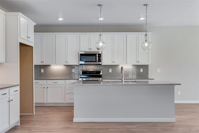 13502 E 100th Ave, Commerce City, CO 80022 - kitchen with appliances with stainless steel finishes, a sink, tasteful backsplash, light wood-type flooring, and white cabinets