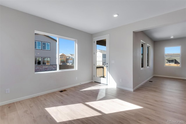 spare room with light wood-type flooring and plenty of natural light