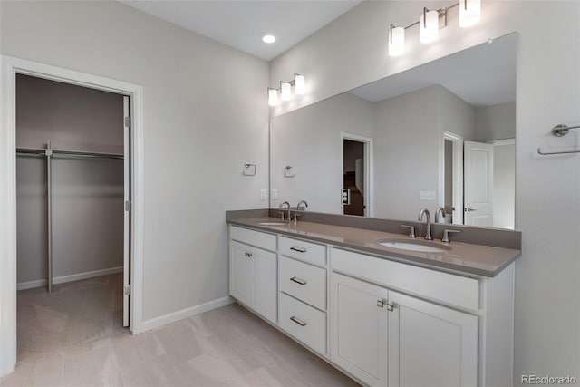 13502 E 100th Ave, Commerce City, CO 80022 - bathroom with a walk in closet, double vanity, baseboards, and recessed lighting