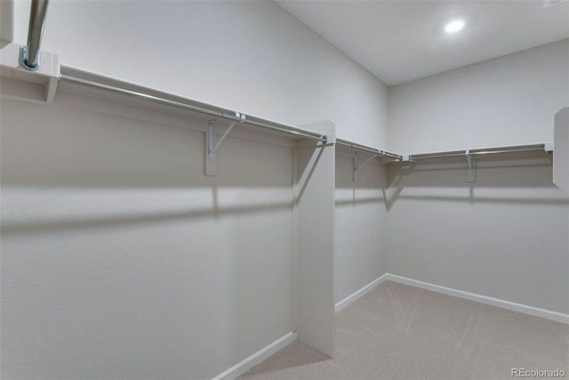 walk in closet with light colored carpet