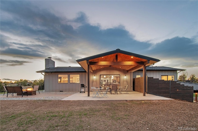 back house at dusk featuring a patio area and an outdoor fire pit