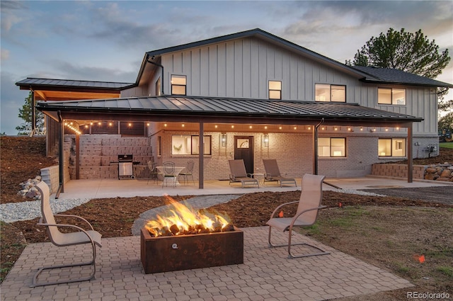 back house at dusk featuring a patio and an outdoor fire pit