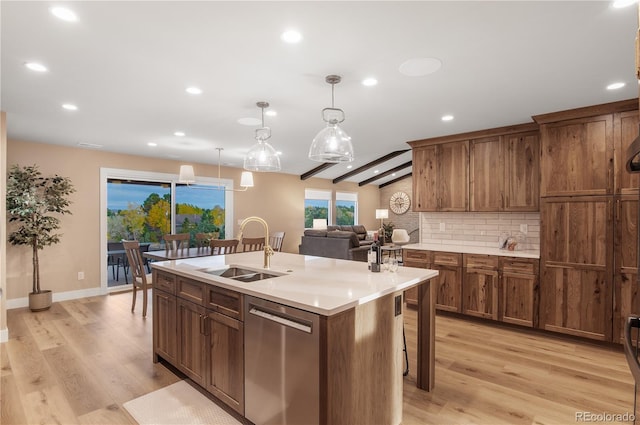 kitchen featuring pendant lighting, sink, a kitchen island with sink, backsplash, and stainless steel dishwasher