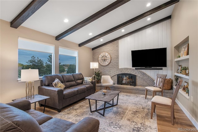 living room with a brick fireplace, beam ceiling, high vaulted ceiling, and light wood-type flooring