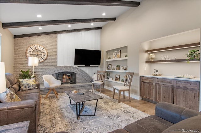 living room featuring lofted ceiling with beams, a fireplace, and light hardwood / wood-style floors