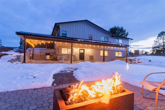 snow covered property featuring a fire pit, a patio, and exterior kitchen