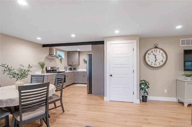 kitchen with stainless steel appliances, light hardwood / wood-style floors, and wall chimney range hood