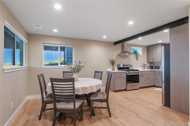 dining room with beam ceiling and light wood-type flooring