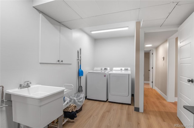 laundry room featuring separate washer and dryer, sink, and light hardwood / wood-style floors