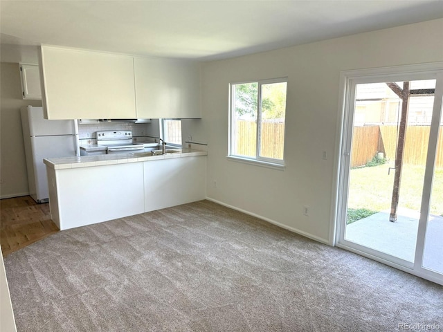 12753 Elm St, Thornton, CO 80241 - kitchen with white appliances, light colored carpet, white cabinets, and a peninsula